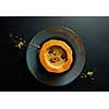 Organic red Uchiki kuri squash or Hokkaido pumpkin cream soup with parsley,on black background