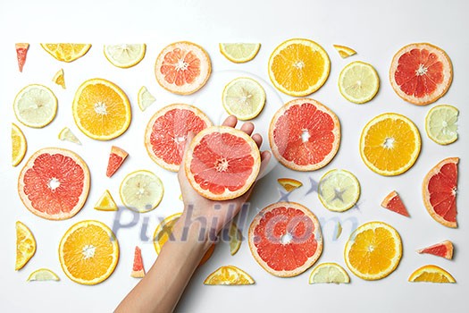 Mix fresh sliced orange, lemon and grapefruit on white background. Female hand putting slice grapefruit, Behind the scenes. Mix fresh sliced orange, lemon and grapefruit on white background. Female hand putting slice grapefruit, Behind the scenes.