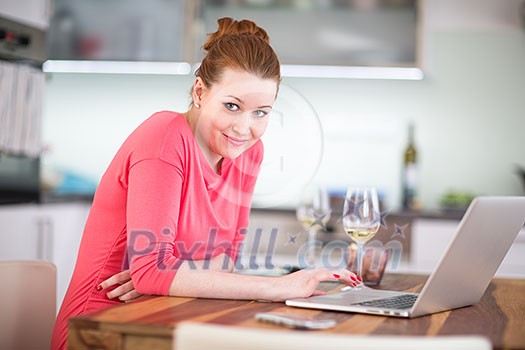 Woman in kitchen with laptop and a glass of wine, browsing the web, shopping online from her modern home (shallow DOF; color toned image) Woman in kitchen with laptop and a glass of wine, browsing the web, shopping online from her modern home (shallow DOF; color toned image)
