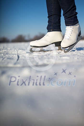 Young woman ice skating outdoors on a pond on a freezing winter day (color toned image; motion blurred image) Young woman ice skating outdoors on a pond on a freezing winter day (color toned image; motion blurred image)