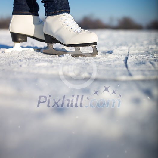 Young woman ice skating outdoors on a pond on a freezing winter day (color toned image; motion blurred image)