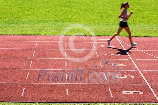 Runner on a running track finishing a race first (motion blurred image) Runner on a running track finishing a race first (motion blurred image)