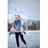 Young woman ice skating outdoors on a pond on a freezing winter day (color toned image; motion blurred image)