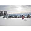 Pretty, young woman snowshoeing in high mountains, enjoying splendid winter weather with abundance of snow