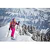 Pretty, young woman snowshoeing in high mountains, enjoying splendid winter weather with abundance of snow