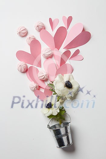 white background with a white flowers in a bucket and paper hearts with meringue white background with a white flowers in a bucket and paper hearts with meringue