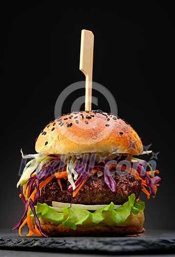 Homemade hamburger with fresh vegetables over black background. Homemade hamburger with fresh vegetables over black background.