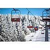 Ski lift with skiers being carried up the hill on a lovely, sunny winter day