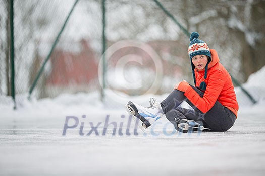 Ice skating concept - young woman sitting on the ice rink after falling down and hurting her knee Ice skating concept - young woman sitting on the ice rink after falling down and hurting her knee