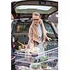 Pretty young woman buying groceries in a supermarket/mall/grocery store - loading the groceries into her car (color toned image; shallow DOF)