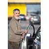 Senior driver getting in his car in a parking lot(color toned image; shallow DOF)