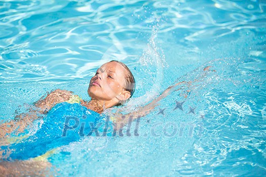 Pretty female swimmer in a pool, getting her daily dose of exercise without stressing her joints Pretty female swimmer in a pool, getting her daily dose of exercise without stressing her joints