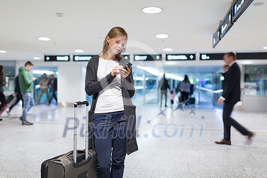 Young female passenger at the airport, using her tablet computer while waiting for her flight (color toned image) Young female passenger at the airport, using her tablet computer while waiting for her flight (color toned image)