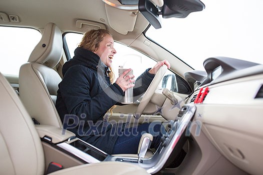 Woman driving a car - female driver at a wheel of a modern car, looking happy, smiling with a relaxed smile (shallow DOF; color toned image) Woman driving a car - female driver at a wheel of a modern car, looking happy, smiling with a relaxed smile (shallow DOF; color toned image)