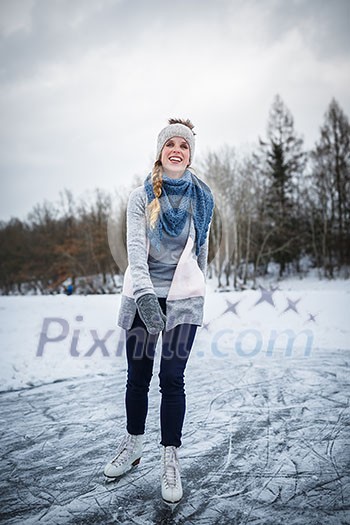 Young woman ice skating outdoors on a pond on a freezing winter day (color toned image; motion blurred image)