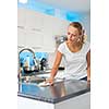 Pretty, young woman in her modern, clean and bright kitchen, cleaning the kitchen (color toned imagey; shallow DOF)