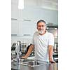 Senior man standing in his renovated, modern kitchen,