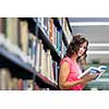 College/university campus - Pretty young female student in library looking for a book (color toned image; shallow DOF)