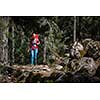 Pretty, young female hiker walking through a splendid old pine forest (shallow DOF)