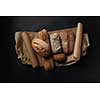 Mix fresh bread on parchment on black background in still life.