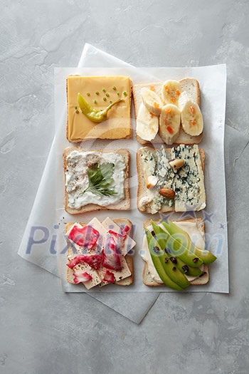 Party starter or appetizer - flat lay composition. Top view of different kinds of colorful sandwiches on white chalkboard background. Food industry concept. Party starter or appetizer - flat lay composition. Top view of different kinds of colorful sandwiches on white chalkboard background. Food industry concept.