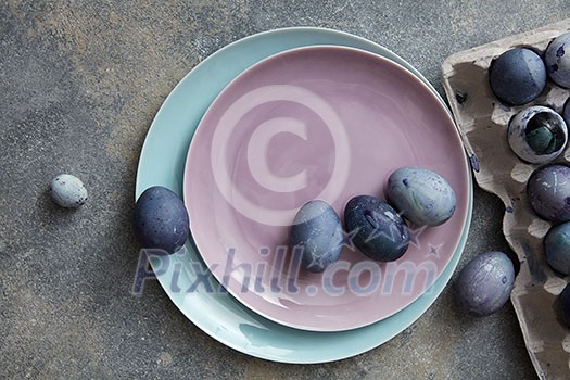 two plates with dyed eggs and a paper tray on a stone table two plates with dyed eggs and a paper tray on a stone table