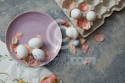 pink plate with eggs and paper tray with dried petals on a concrete background pink plate with eggs and paper tray with dried petals on a concrete background