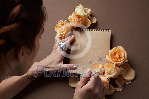 Woman writing love sign in notepad with orange roses Woman writing love sign in notepad with orange roses