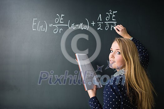 Pretty, young college student writing on the chalkboard/blackboard during a math class (colort toned image; shallow DOF) Pretty, young college student writing on the chalkboard/blackboard during a math class (colort toned image; shallow DOF)