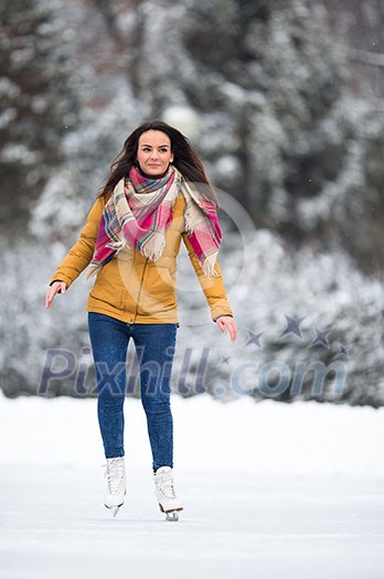 Young woman ice skating outdoors on a pond on a freezing winter day (color toned image; motion blurred image) Young woman ice skating outdoors on a pond on a freezing winter day (color toned image; motion blurred image)