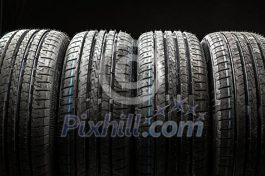 Stack of brand new high performance car tires on clean low-key black studio background Stack of brand new high performance car tires on clean low-key black studio background