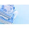 Stack of boy infant clothing for baby shower on blue background