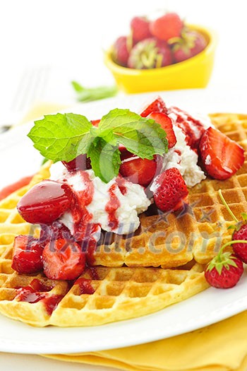 Plate of belgian waffles with fresh strawberries and whipped cream