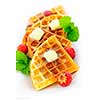 Plate of belgian waffles with fresh strawberries and pats of butter