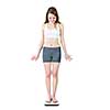 Happy fit young woman standing on bathroom scale looking down