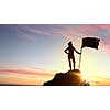 Silhouette of young woman with flag on mountain top