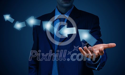 Businessman holding arrows in palm over dark background Businessman holding arrows in palm over dark background