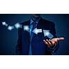 Businessman holding arrows in palm over dark background