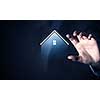 Close up of businesswoman holding real estate icon in palm on dark background