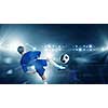 Rear view of kid boy in blue uniform on soccer stadium kicking ball
