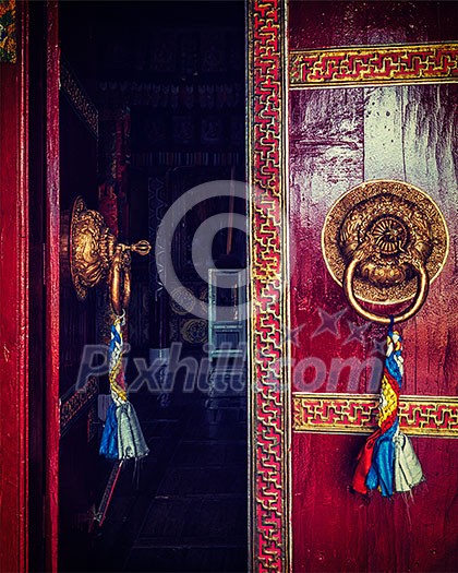 Vintage retro effect filtered hipster style image of open door of Spituk Gompa (Tibetan Buddhist monastery) with ornamented decorated door handle. Ladakh, India Vintage retro effect filtered hipster style image of open door of Spituk Gompa (Tibetan Buddhist monastery) with ornamented decorated door handle. Ladakh, India