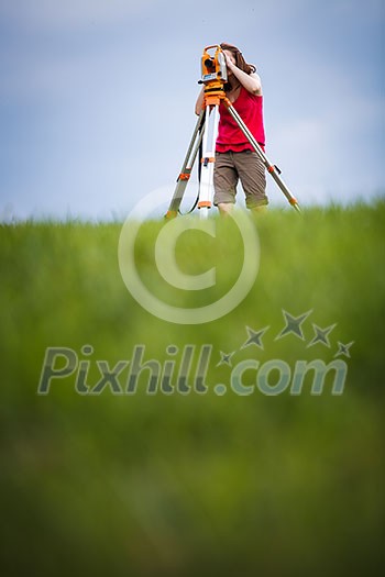 Young, female land surveyor at work - using the theodolite level outdoors Young, female land surveyor at work - using the theodolite level outdoors