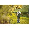 Senior man mowing the lawn in his garden (selective focus; shallow DOF)