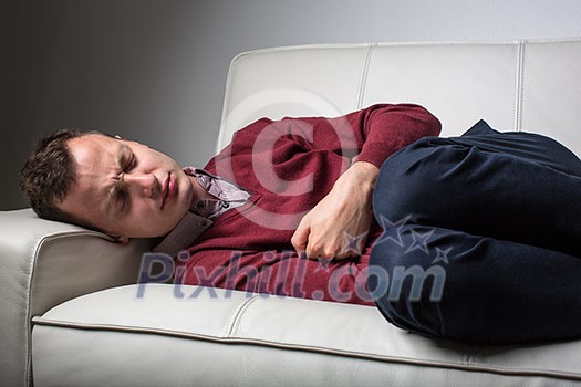 Young man suffering from severe belly pain, being cornered by the debilitating condition of celiac disease/Crohn's disease