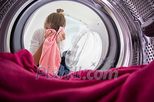 Young woman doing laundry - view from the washing machine Young woman doing laundry - view from the washing machine