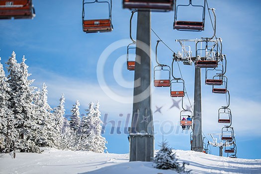 Ski lift with skiers being carried up the hill on a lovely, sunny winter day