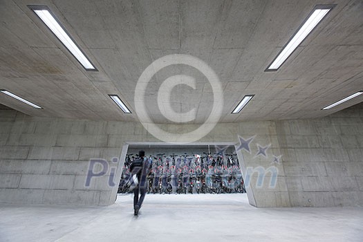 Modern trainstation with bikestands rush - man walking to get his bike and commute home (color toned image;motion blurred image) Modern trainstation with bikestands rush - man walking to get his bike and commute home (color toned image;motion blurred image)
