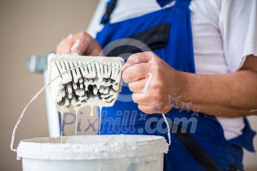 Painter man at work with a paint bucket, wall painting concept Painter man at work with a paint bucket, wall painting concept