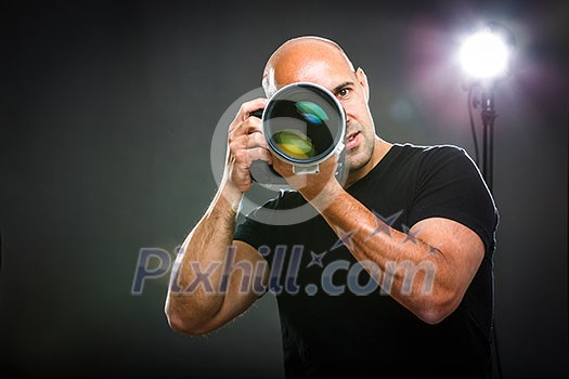 Young, pro male photographer in his studio during a photo shoot (color toned image; shallow DOF) Young, pro male photographer in his studio during a photo shoot (color toned image; shallow DOF)