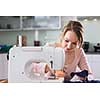 Beautiful young woman sewing clothes with sewing machine (color toned image; shallow DOF)